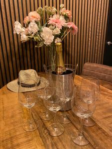 a table with wine glasses and a vase with flowers at Camping Kleine Belterwijde, Wiede Lodge met uitzicht over het water in Belt-Schutsloot
