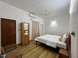 a bedroom with a bed and a wooden floor at Tess Holistay Fort Kochi in Fort Kochi