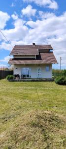 a white house with a brown roof on a field at Sienas Holiday Home in Vrnjačka Banja