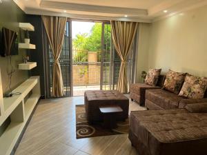 - un salon avec un canapé et une grande fenêtre dans l'établissement Del Cielo Serviced Apartments, à Entebbe