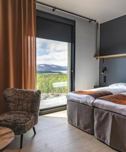 ein Schlafzimmer mit einem Bett und einem Stuhl sowie einem großen Fenster in der Unterkunft Cahkal Hotel in Kilpisjärvi