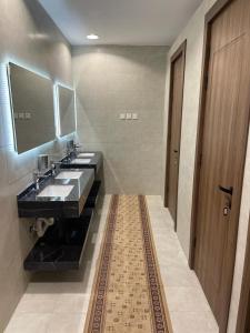 a bathroom with two sinks and a mirror at Aya Hostel in Al Madinah