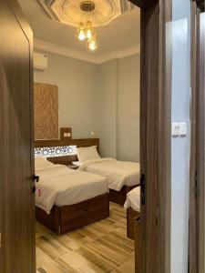 a bedroom with two beds and a chandelier at Aya Hostel in Al Madinah