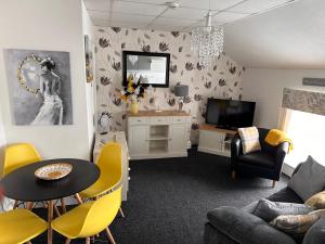 a living room with a table and yellow chairs at Berkswell Holiday Apartments in Blackpool