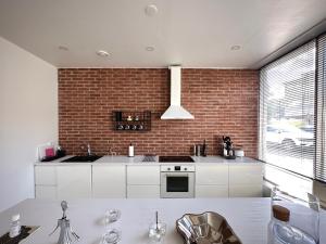 a kitchen with white cabinets and a brick wall at Lomahuoneisto Wanha Vääksy in Vääksy