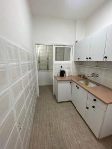 a white kitchen with white cabinets and a sink at Teper Apartment in Bat Yam