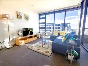 uma sala de estar com um sofá azul e uma televisão em Comfy & Bright 1 Bed Apt Olympic em Sydney