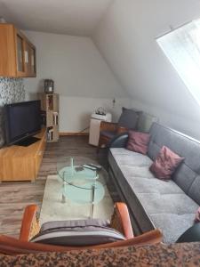 ein Wohnzimmer mit einem Sofa und einem Glastisch in der Unterkunft Ferienwohnung Annett in Böhlen