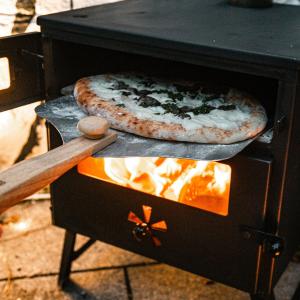 two pizzas are cooking in a stove with a pizza at Cosy private Glamping with Pizza stove, Big Projector Screen, own hot Monsoon shower, breakfast - Glamping with a difference! in Tenby