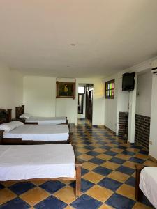 Habitación con 4 camas y suelo a cuadros. en Hotel Campestre Los Chiguiros, en Villavicencio