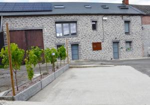 un bâtiment en briques avec un garage et des arbres devant lui dans l'établissement Gîtes Paille-Foin, à Cerfontaine