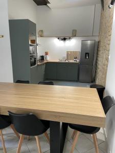 une cuisine avec une table en bois et des chaises noires dans l'établissement Atypique - Centre historique - Appartement 2 chambres, à Bourges