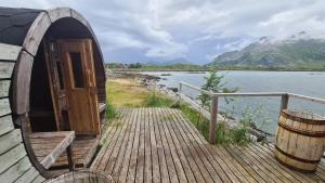 a small building with a door on a dock next to the water at Lydersen Rorbuer Budget Hostel & Private Apartments in Fredvang