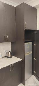 eine Küche mit dunkelbraunen Schränken und einem Kühlschrank in der Unterkunft Green house - Apartment 1g - 17 in Rustawi + 28 Fotos