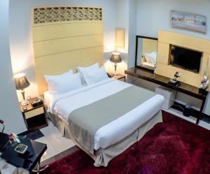 una camera con un grande letto bianco e una TV di Doha Dynasty Hotel a Doha Altre 26 foto