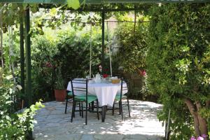 una mesa y sillas bajo una pérgola en un jardín en La Casa di Nonna, en Qeparo