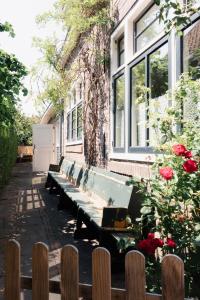 eine Reihe von Bänken vor einem Gebäude mit Rosen in der Unterkunft Bed and breakfast Jan in Edam