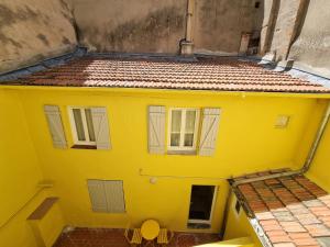 een uitzicht op een geel huis met twee ramen bij etienne dollet in Béziers