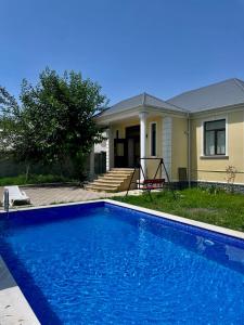 a blue swimming pool in front of a house at EMIREST Villa in Gabala