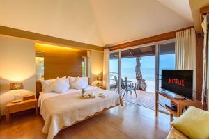 a bedroom with a bed with a television and a balcony at Veranda Lodge in Hua Hin
