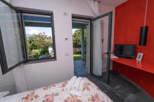 1 dormitorio con 1 cama, TV y ventana en Giacaranda B&B, en Castellabate