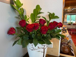 un vase blanc rempli de roses rouges sur une table dans l'établissement Elisabeth Serfaus inkl der SUPER SOMMER CARD im SOMMER 2024, à Serfaus