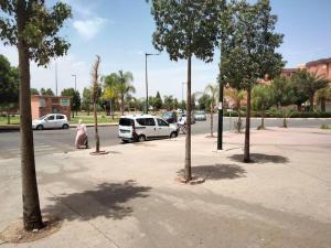 uma rua com carros estacionados num parque de estacionamento com árvores em Apartment in the center of marrakech for a good price em Marrakech