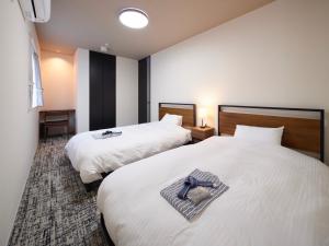a hotel room with two beds with a cross on them at プライバシースイート伊豆高原 in Yawatano