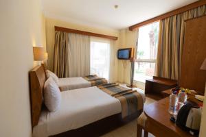 a hotel room with two beds and a window at Empire Beach Aqua Park in Hurghada