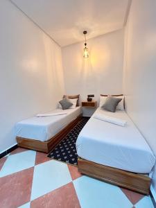 two beds in a room with a checkered floor at Salam appartement in Azrou