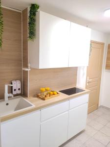 a kitchen with white cabinets and fruit on a cutting board at Chambre simple climatisée - Proche Tram & Centre in Montpellier