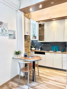 una cocina con armarios blancos y una mesa y sillas de madera. en B&B La Dimora di Tommaso Apartment - Dimora storica Bike Friendly, en Ortona