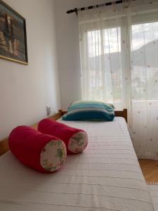 2 camas con almohadas rojas en una habitación con ventana en Guest House Villa Kosa, en Bijela