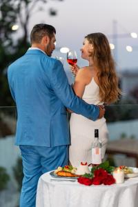 a man and woman standing next to a table with a glass of wine at Blue Harbour Boutique in Ayia Napa