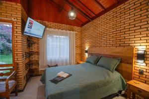 a bedroom with a bed with a book on it at Chalé Flores e Amores in Visconde De Maua