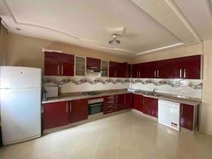 een keuken met rode kasten en een witte koelkast bij Magnifique villa-résidence calme 1,5km de la plage in Saidia 