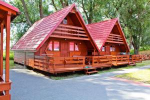 a large wooden cabin with a red roof at Domki letniskowe Ibiza in Dźwirzyno
