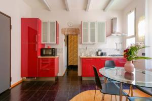 kuchnia z czerwonymi szafkami i stołem z krzesłami w obiekcie Maison N14 w Bolonii