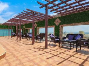 d'une terrasse avec des chaises et un mur vert. dans l'établissement هوليداي الخليج الخبر Holiday Al Khaleej Hotel, à Khobar