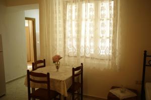 un tavolo con un vaso di fiori e una finestra di La Casa di Nonna a Qeparo