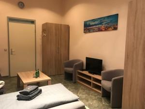 a room with a bed and a tv and chairs at Pension Lotti Friedrichshain in Berlin