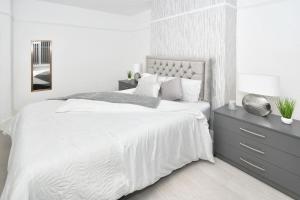 a white bedroom with a large bed and a nightstand at Frilsham House by YourStays in Stoke on Trent
