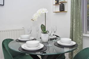 a glass table with plates and glasses on it at Book Frilsham House by YourStays, Your Ultimate Home Away From Home featuring 3 bedrooms and 2 bathrooms - Secure YourStays today! in Stoke on Trent