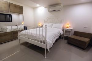 a bedroom with a white bed and a chair at Tony Guesthouse in ‘Akko