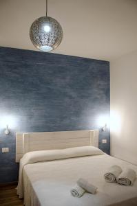1 dormitorio con 1 cama grande y pared azul en Appartamenti La Baia del Raìs, en Falcone