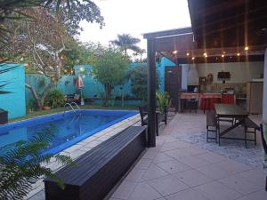 einen Hinterhof mit einem Pool und einer Terrasse mit einem Tisch in der Unterkunft CASA SERENA - Piscina, Wi-fi e Conforto bem pertinho da praia in Itanhaém