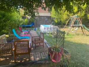 un patio trasero con un parque infantil con sillas y columpios en maison en pierre atypique sur jardin paysagé, 