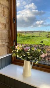um vaso com flores sentado no peitoril da janela em The Cow Shed - Rural Barn Conversion em Little Bytham