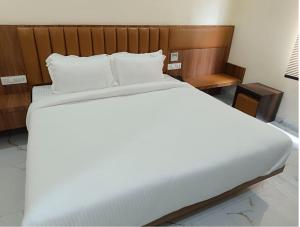 ein großes Bett mit weißer Bettwäsche und einem Kopfteil aus Holz in der Unterkunft Hotel Paramveer in Muzaffarpur