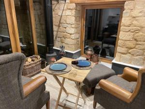 a table and two chairs in a room with a fireplace at The Cow Shed - Rural Barn Conversion with Hot Tub in Little Bytham